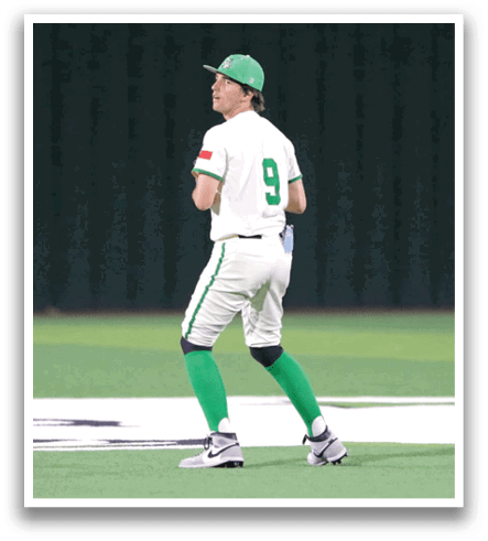 A baseball player wearing a green hat and white uniform is walking on the field. Contenido generado con IA
