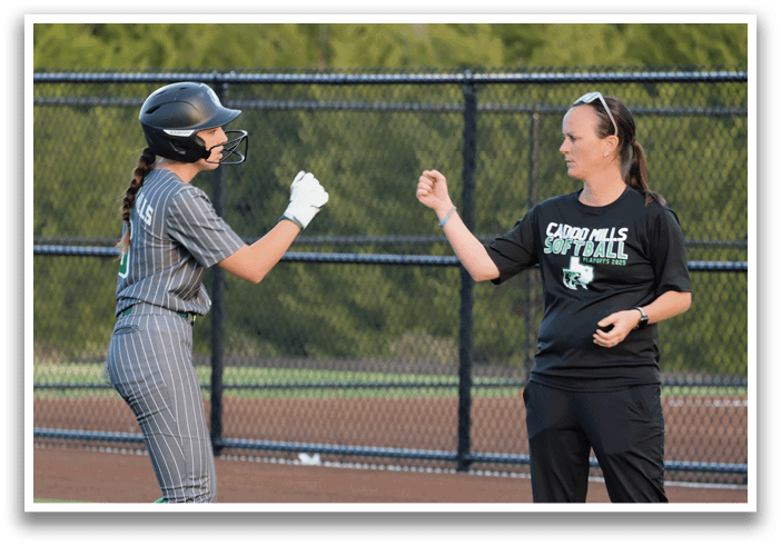 Two women are talking on a baseball field. One woman is wearing a baseball uniform and the other is wearing a black shirt. Contenido generado con IA