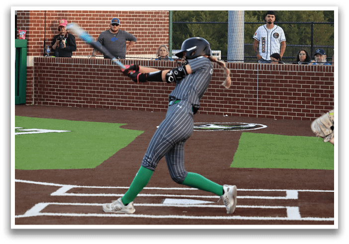 A female baseball player is swinging a bat, attempting to hit a ball. Contenido generado con IA
