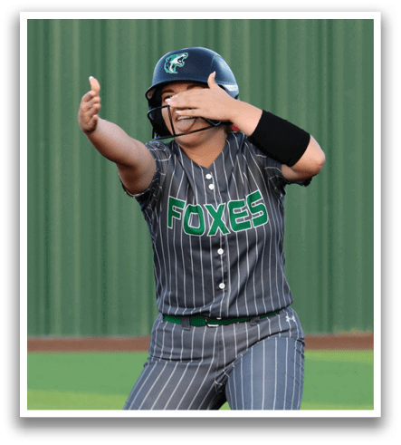 A female baseball player wearing a grey and green uniform is standing on a base. Contenido generado con IA
