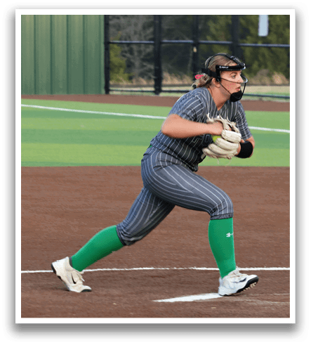 A female baseball player in a grey and black striped uniform is running towards home plate. Contenido generado con IA