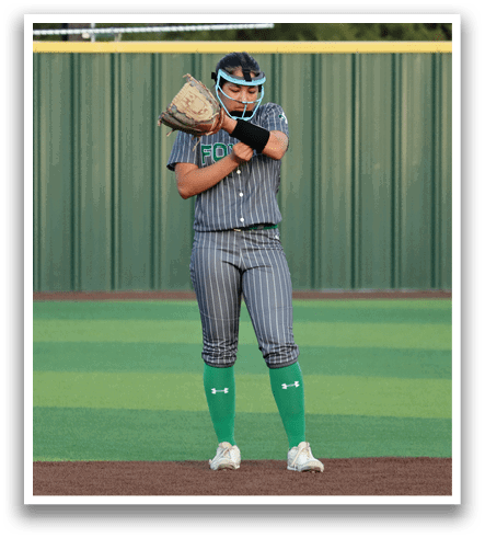 A female baseball player in a grey and green uniform is on the pitcher's mound, holding a baseball glove and preparing to throw the ball. Contenido generado con IA