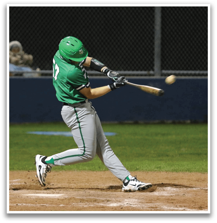 A baseball player in a green shirt and grey pants is swinging a bat at a ball. Contenido generado con IA