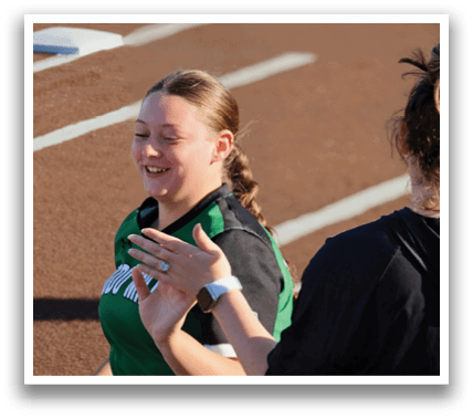 A woman wearing a green shirt and black shorts is smiling and waving at someone. Contenido generado con IA