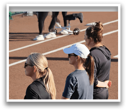 Three women wearing black and white hats are standing on a track. Contenido generado con IA
