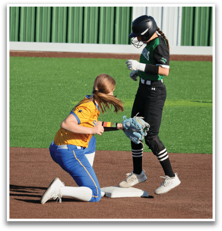 Two female baseball players on the field, one is kneeling down and the other is standing. Contenido generado con IA