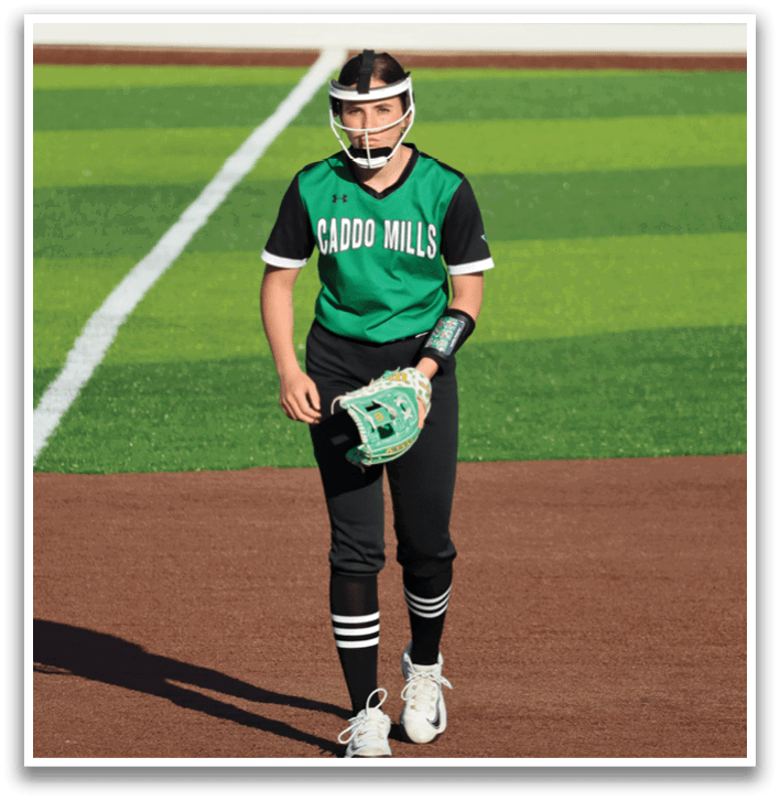 A female baseball player wearing a green and black uniform walks across the field while holding a catcher's mitt. Contenido generado con IA