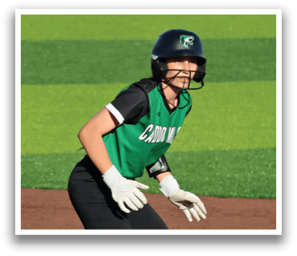 A female baseball player wearing a green and black uniform, standing on the field with her hands on her knees. Contenido generado con IA