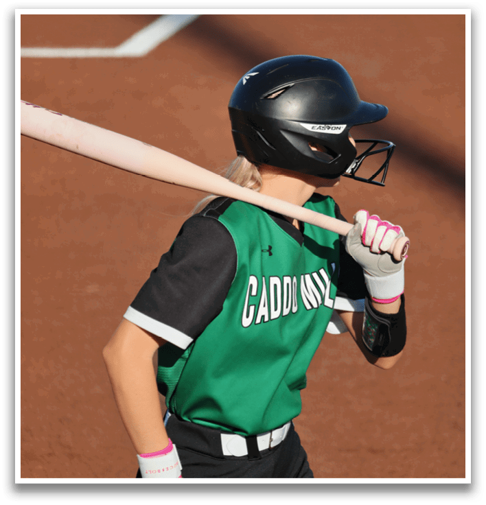 A girl in a green and black baseball uniform is holding a bat and getting ready to swing. Contenido generado con IA