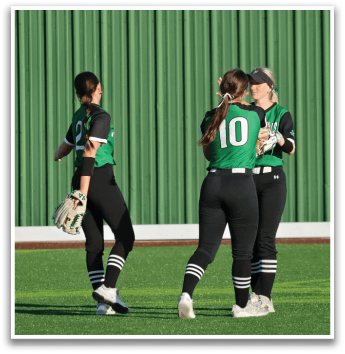 Three female softball players are hugging each other on the field. Contenido generado con IA