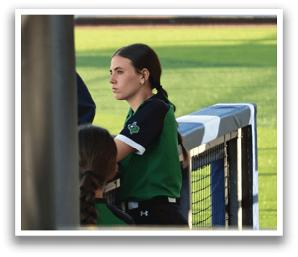 A woman wearing a green and black shirt is sitting on a bench. Contenido generado con IA