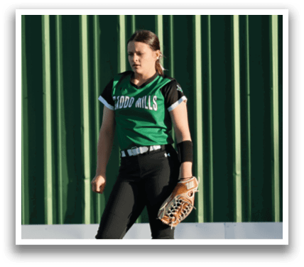 A woman wearing a green shirt and black pants stands on a grassy field. She is holding a baseball glove. Contenido generado con IA