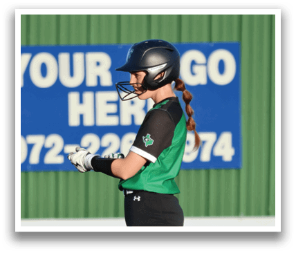 A woman in a green and black uniform stands on a baseball field, holding a baseball bat. Contenido generado con IA