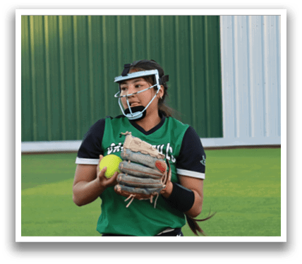A female baseball player wearing a green shirt and black shorts, holding a baseball glove and a ball. Contenido generado con IA