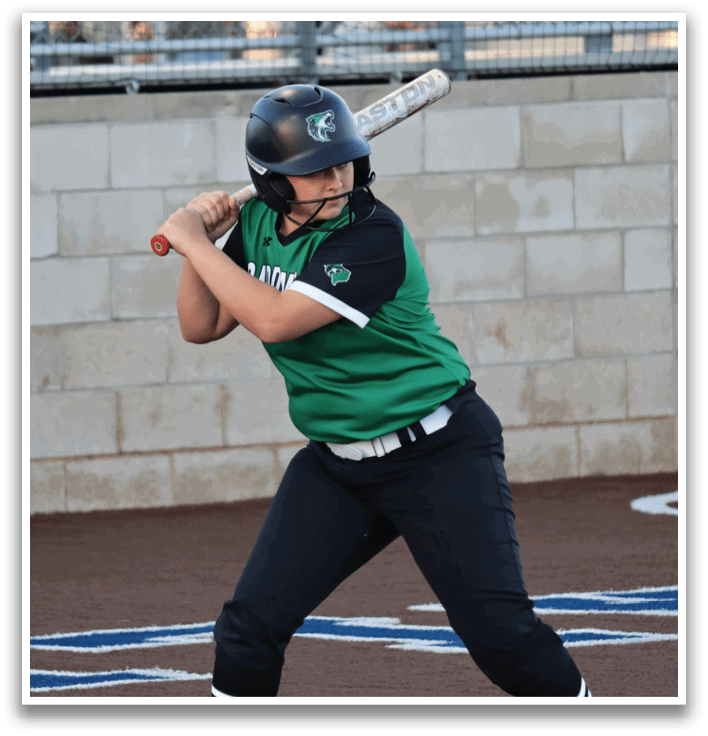 A woman in a green and black uniform is swinging a baseball bat, preparing to hit the ball. Contenido generado con IA