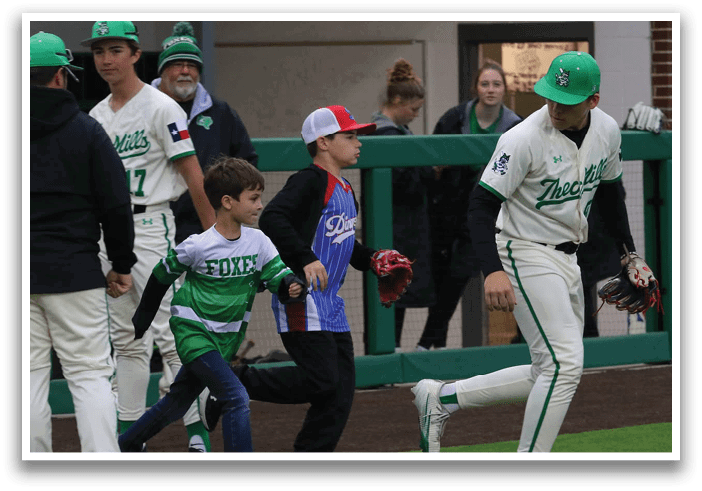 A group of people, including a boy and a man, are walking on a field. The man is wearing a baseball uniform and a cap. Contenido generado con IA