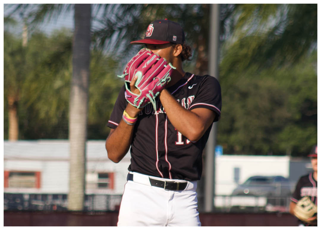 A baseball player in a black and red uniform is standing on the pitcher's mound. Description generated by AI