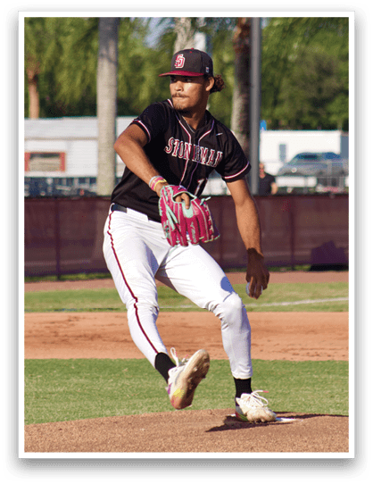 A baseball player in a black and red jersey throws a pitch. Description generated by AI