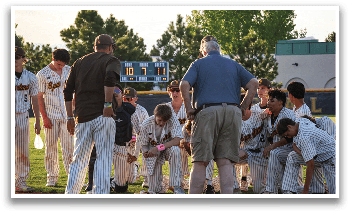 A group of baseball players huddled together on a field, with a man in a brown shirt and tan shorts talking to them. AI generated content