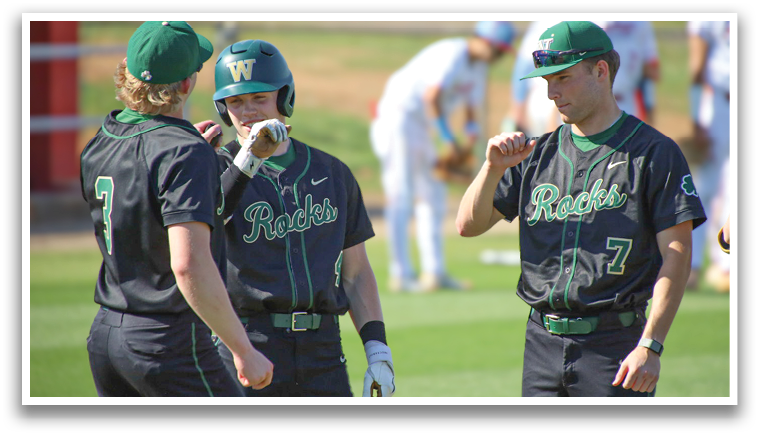 Four baseball players wearing black jerseys and green hats are standing on a field. They are talking to each other and one of them is holding a baseball bat. AI generated content