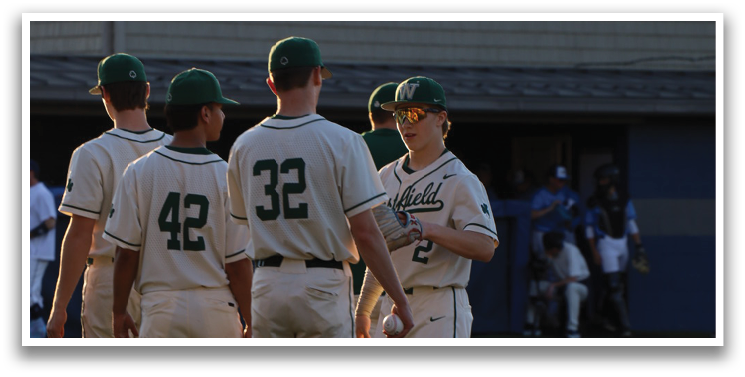 Four baseball players wearing white uniforms and green hats stand on a field. AI generated content