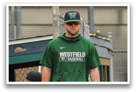 A man wearing a green Westfield baseball shirt stands on a baseball field. AI generated content