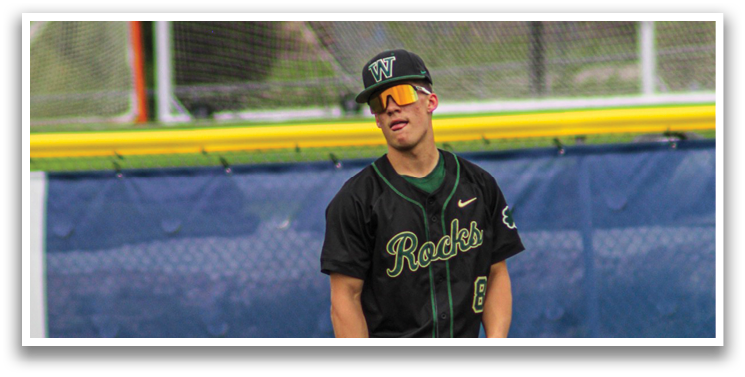 A baseball player wearing a black and green jersey and a hat with a yellow logo. He is holding a baseball glove and standing on a grassy field. AI generated content