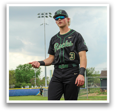 A baseball player wearing a black and green jersey stands on a field. AI generated content