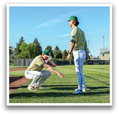 Two men are standing on a grassy field, one of them is wearing a baseball uniform. AI generated content