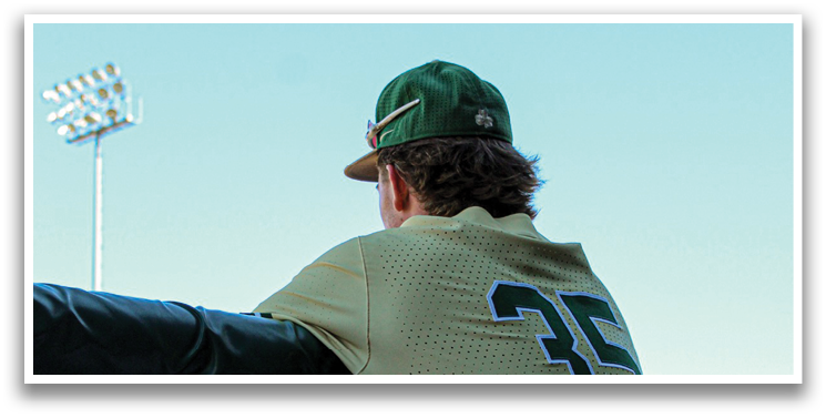 A baseball player wearing a green and white uniform is leaning on a fence. AI generated content