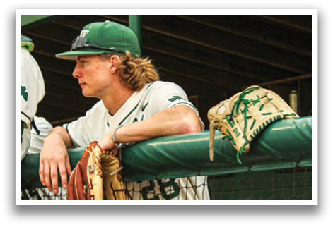 A baseball player wearing a green hat and white uniform sits on a bench with his glove on his lap. AI generated content