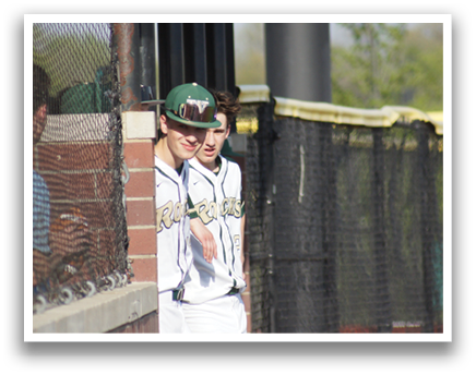Two men wearing baseball uniforms are standing behind a fence, looking at something. AI generated content