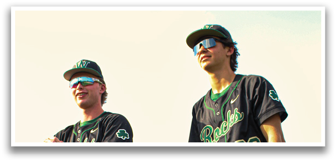 Two baseball players wearing black and green uniforms are walking on a grassy field. AI generated content