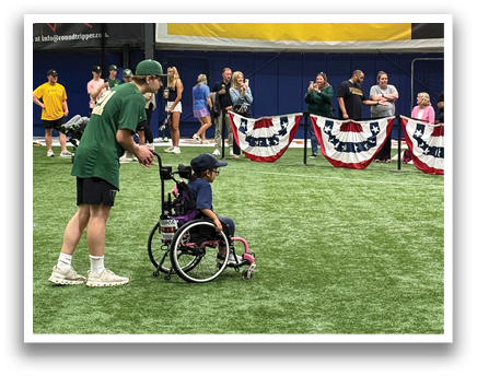 A group of people are gathered in a field, with some sitting in wheelchairs and others standing. They are watching a baseball game, with a sports ball visible in the scene. AI generated content