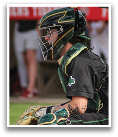A baseball player wearing a green and black uniform is sitting on the ground with his catcher's mitt on. AI generated content