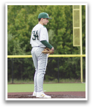 A baseball player wearing a green and white uniform stands on the pitcher's mound. Description generated by AI