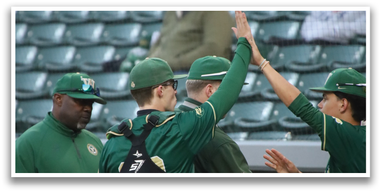 A group of men wearing green shirts and green hats. Description generated by AI