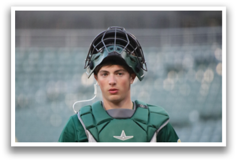 A baseball player wearing a green shirt and green catcher's gear. Description generated by AI
