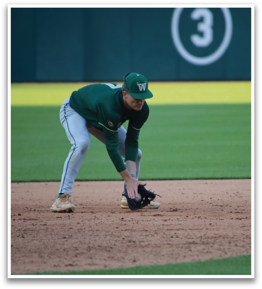 A baseball player is bending over to catch a ball. Description generated by AI