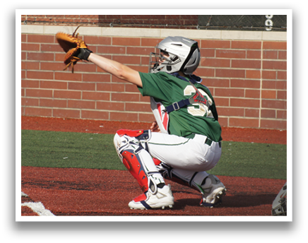 A baseball player wearing a green shirt and red pants is kneeling on the ground. Description generated by AI