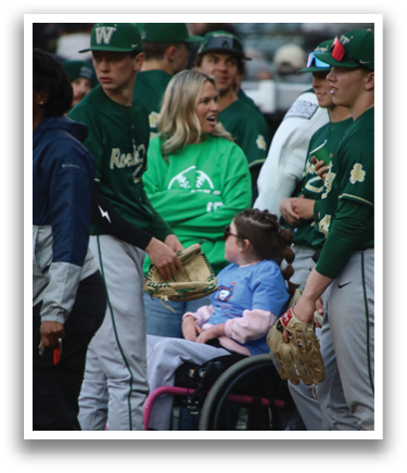 A group of people standing around a woman in a wheelchair. Description generated by AI