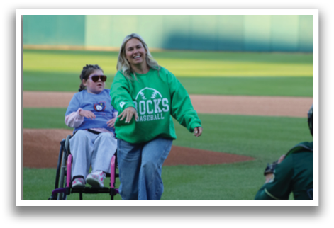 A woman in a green shirt and a wheelchair is throwing a baseball. Description generated by AI