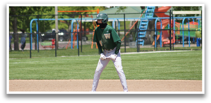 A baseball player in a green and white uniform is standing on a baseball field. Description generated by AI