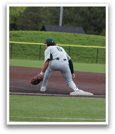A baseball player in a green and white uniform is bending over to catch a ball. Description generated by AI