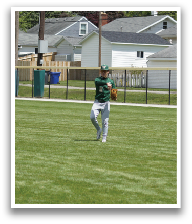 A baseball player in a green shirt and white pants is throwing a ball. Description generated by AI