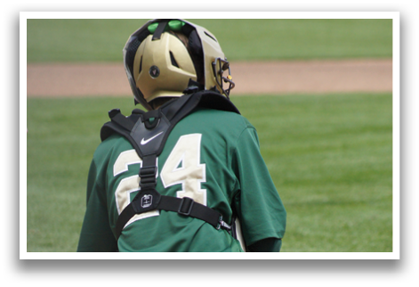 A baseball catcher wearing a green and white uniform. Description generated by AI