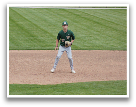 A baseball player in a green and white uniform is standing on the field. Description generated by AI