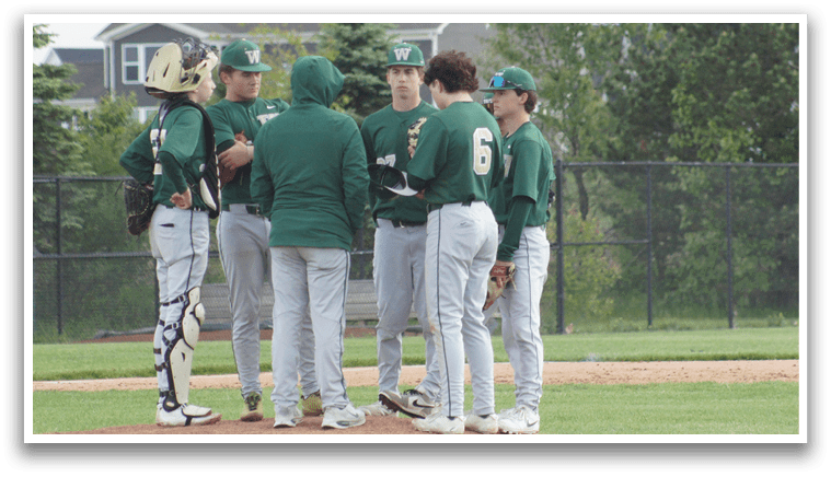 A group of baseball players wearing green and white uniforms. Description generated by AI