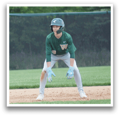 A baseball player in a green and white uniform is standing on the field. Description generated by AI