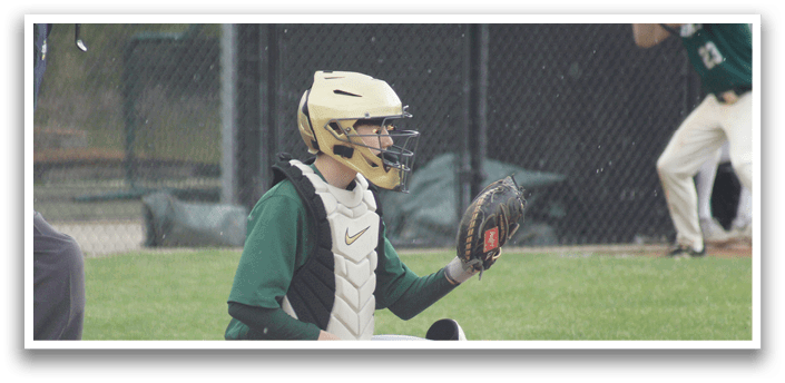 A baseball player wearing a green and white uniform is sitting on the ground with a catcher's mitt on his left hand. Description generated by AI